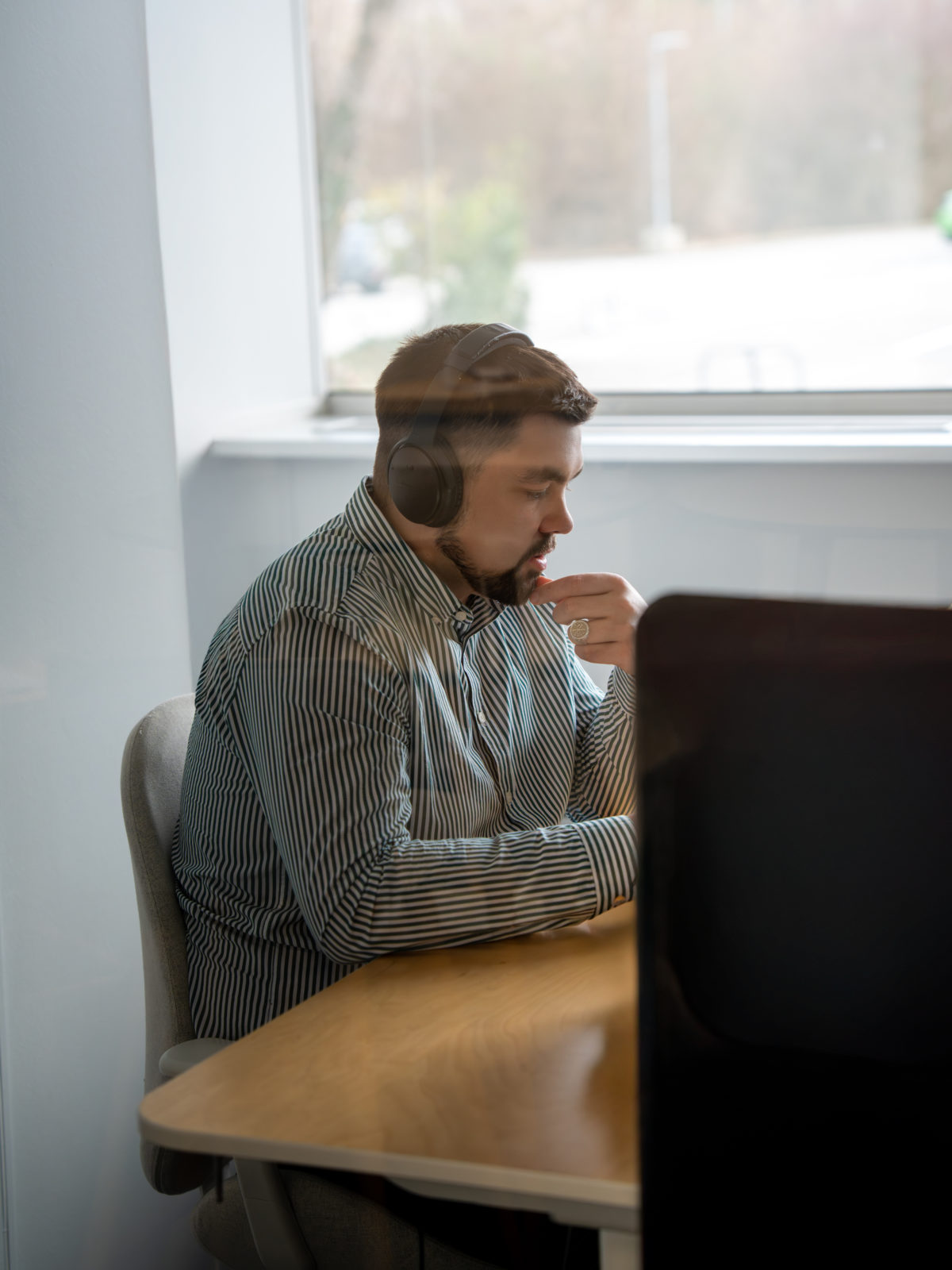 Homme avec un casque sur les oreilles assis sur un bureau